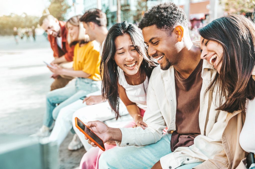 Diverse group of young people using mobile phone device outside